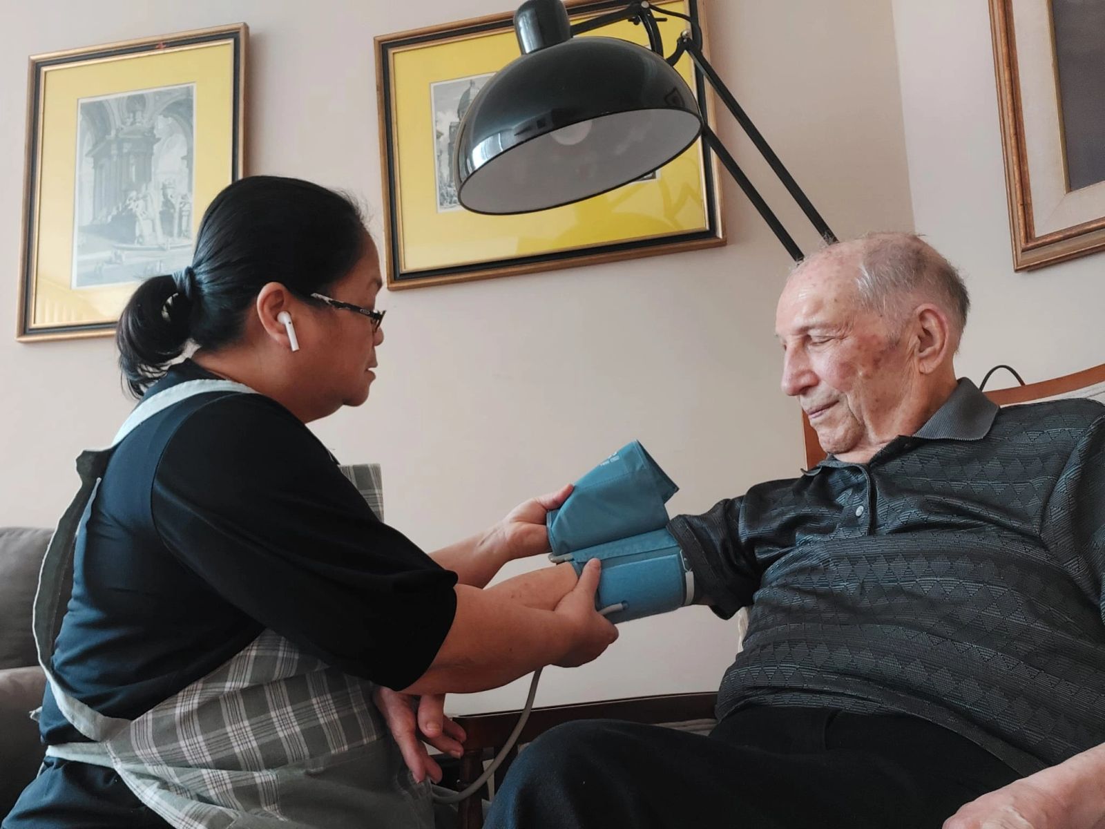 One of our caregivers checking a beloved client's blood pressure at home